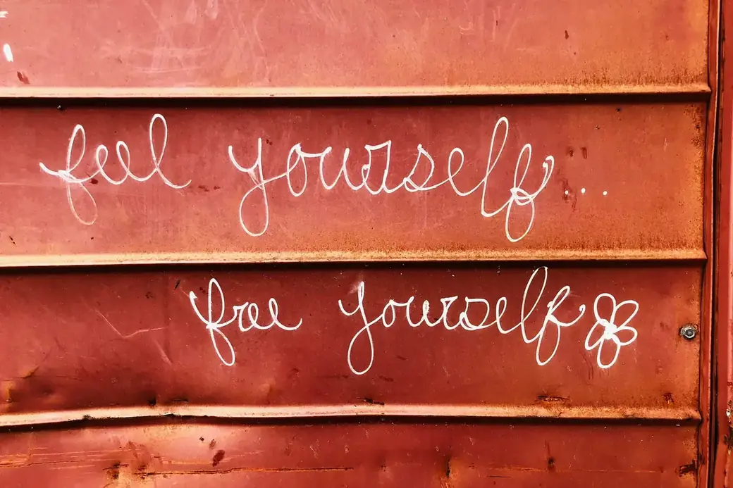 Schriftzug &bdquo;feel yourself &ndash; free yourself&ldquo; auf einer rostroten Containerwand